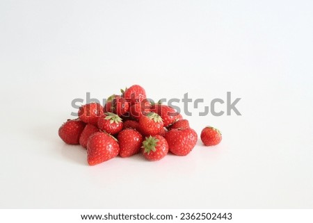 Close-up picture of a pile of fresh strawberries on a white table, white background, no people, healthy summer snack, organic nordic berries, flat lay image, sweet juicy berries, focus on details