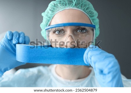 Woman doctor sealing her mouth with blue tape. Medical secrecy concept Royalty-Free Stock Photo #2362504879