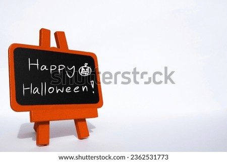 Happy Halloween text on orange sign located on with background with copy space. Hand writing on blackboard.