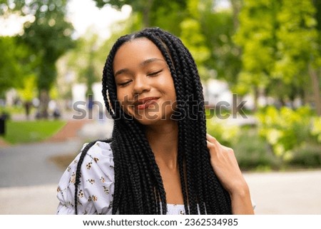 Portrait of a young pretty afro woman with pigtails who smiles and closes her eyes in pleasure. Royalty-Free Stock Photo #2362534985