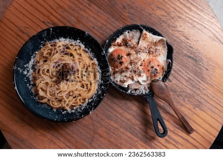Two delicious plates with detailed and beautiful plate decorations. A carbonara with a plate of eggs.