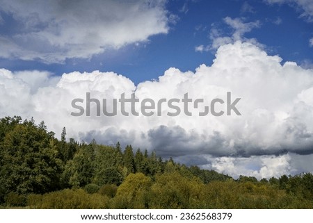 white rain clouds over countryside in summer with blue sky and high contrast