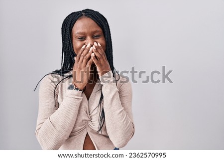 African woman with braids standing over white background laughing and embarrassed giggle covering mouth with hands, gossip and scandal concept 