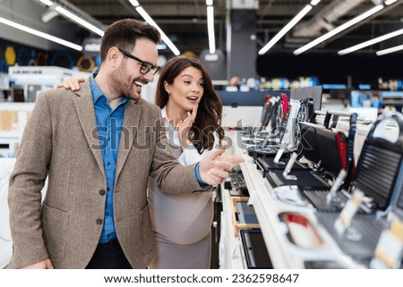 Beautiful and happy middle age couple buying consumer tech products in modern home tech store. They are choosing small kitchen appliances. People and consumerism concept. Royalty-Free Stock Photo #2362598647
