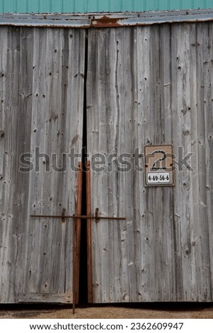 a locked door to a weathered and old grey wood farm building