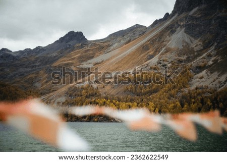 Landscape picture of the Sils lake in Switzerland during a cloudy autumnal day, with flags in the foreground