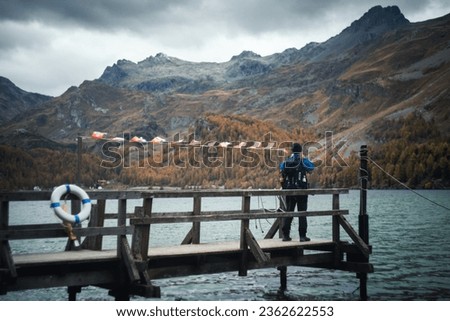 A photograper takes pictures of the Sils lake in Switzerland during a cloudy autumnal day