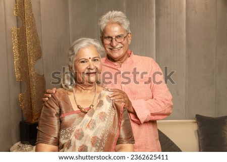 Senior handsome indian asian man presenting his wife looking in front of the camera on diwali or anniversary. happy diwali theme concepts wearing indian traditional ethnic kurta pajama and saree. Royalty-Free Stock Photo #2362625411