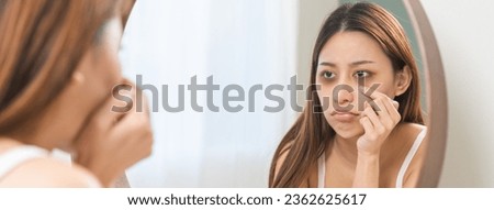 Bored, insomnia asian young woman, girl looking at mirror hand touching under eyes with problem of black circles or panda puffy, swollen and wrinkled on face. Sleepless, sleepy healthcare person.
