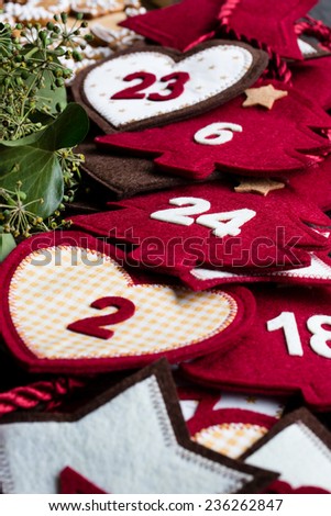 Advent calendar of red and white symbols and numbers with ivy wreath and gingerbread in the background