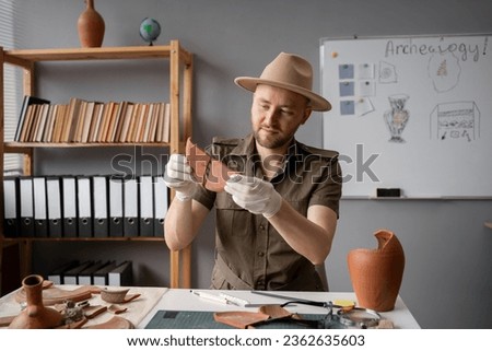 Archeologist working with piece of antique plate in office. Copy space Royalty-Free Stock Photo #2362635603