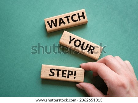 Watch your Step symbol. Concept words Watch your Step on wooden blocks. Businessman hand. Beautiful grey green background. Business and Watch your Step concept. Copy space.