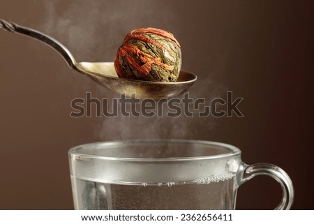 Chinese green tea ball with jasmine and marigold (calendula) flowers, ready to prepare. Green tea and mug with hot water.