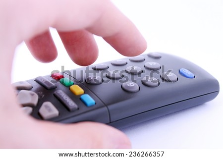Close up studio shot of hand pressing remote control button isolated on white background