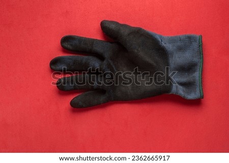 Black hand protection glove on red background