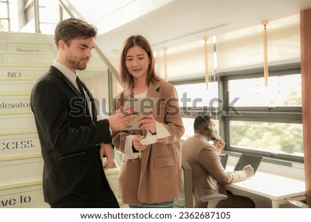business people lady and caucasian smart man with smart tablet and talk presentation at indoor stairs way. team of business people walk in rush hour at indoor pedestrian stairs and talk together.