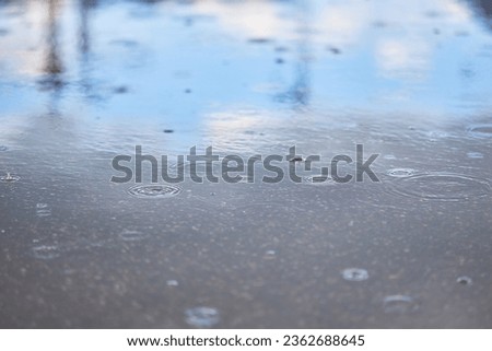 Heavy rain falling on the asphalt, puddles with splashes from drops..