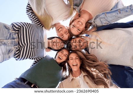 Multiracial group of young beautiful people standing in circle and smiling excited at camera. Happy diverse generation z friends having fun embracing together. Low angle view sunny portrait outdoor. Royalty-Free Stock Photo #2362690405