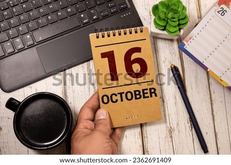 Wooden calendar with date October 16 and alarm clock on table against brick wall background. Deadline, planning, business concept