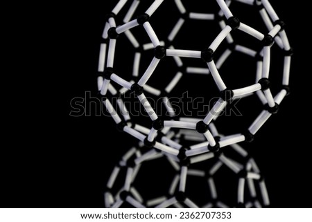 Image of atomic structure model of carbon fullerene sphere with blurred mirror reflection and black background