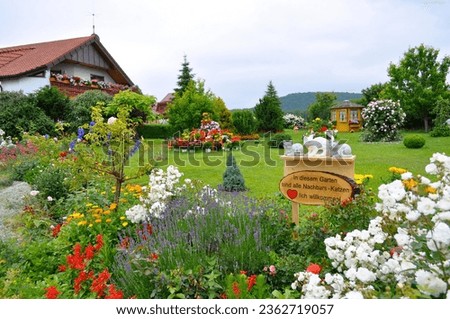 Pyramid of flowers in the garden, sign : cats welcome in the garden, white roses in the garden