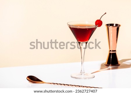 Black Manhattan alcoholic cocktail with whiskey and red vermouth garnished with maraschino cherry in martini glass. Beige background, hard light Royalty-Free Stock Photo #2362727407
