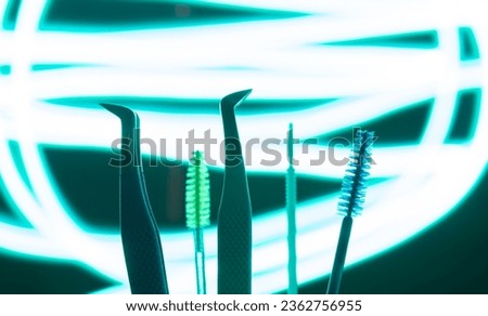 Green mascara and tweezers in green background