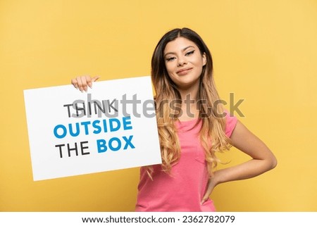 Young Russian girl isolated on yellow background holding a placard with text Think Outside The Box with happy expression