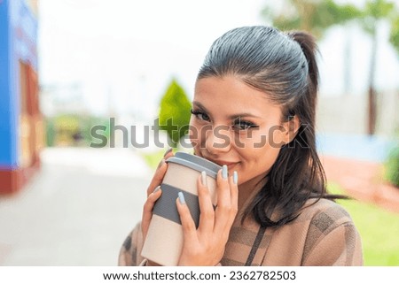 Young pretty woman at outdoors holding a take away coffee
