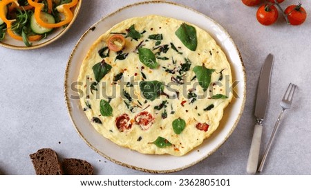 A wholesome breakfast of spinach omelette, cherry tomatoes, grated cheese, fresh veggies, and whole grain bread Royalty-Free Stock Photo #2362805101