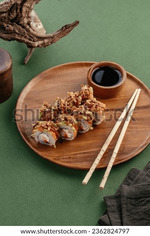 Sushi and soy sauce in a bowl and wooden chopsticks on a gray wooden table. Japanese food. 