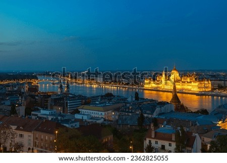 A picture of Budapest landmarks at night, such as the Hungarian Parliament, the Church of Stigmatisation of Saint Francis, the Saint Anne Parish Church, and the Szilagyi Dezso Square Reformed Church.