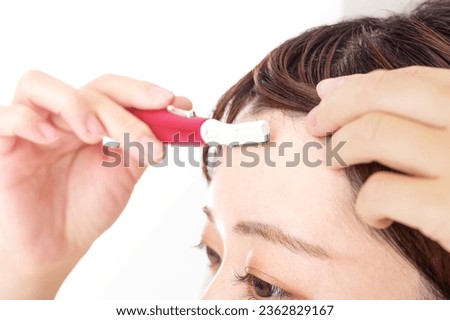 A woman who treats unwanted hair on her face with an electric trimmer Royalty-Free Stock Photo #2362829167