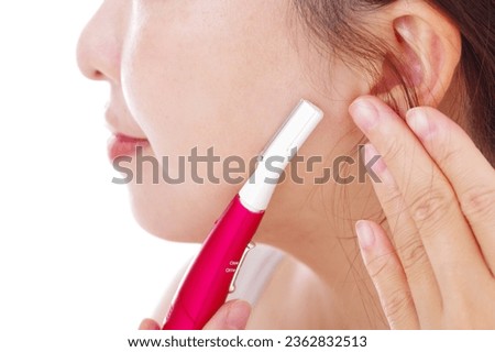 A woman who treats unwanted hair on her face with an electric trimmer Royalty-Free Stock Photo #2362832513