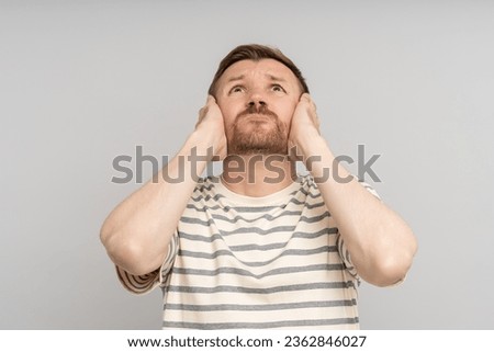 Man covers ears with hands looks up. Annoying noise loud sharp sounds. Sensory overload. Suffering from throbbing ear ache. Noisy neighbours stressed by hum avoid listening vociferous fight from above Royalty-Free Stock Photo #2362846027