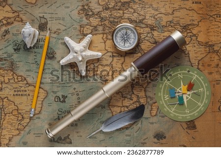Spyglass, a compass, a starfish, a pencil and a bird's feather - the symbol of travelers lie on an old map. View from above
