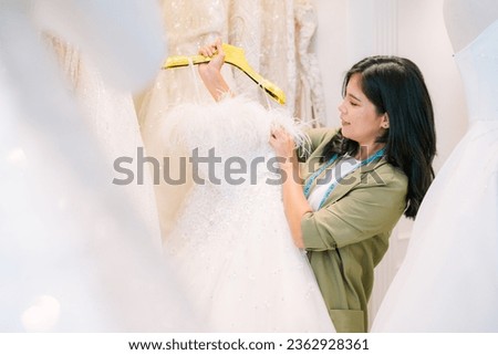 Portrait of entrepreneur bridal shop owner business woman fashion designer stylish working. Attractive designer girl using tape meter fitting on wedding dress with mannequin at wedding studio.