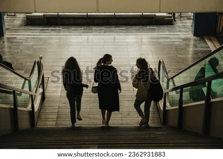Three girls walking downstairs at the shopping mall. Back view shot.