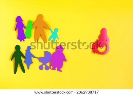 The concept of society's attitude towards people with disabilities. Colored cardboard figures of people on a light background
