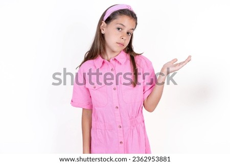 Beautiful kid girl wearing pink dress over white background smiling cheerful presenting and pointing with palm of hand looking at the camera.