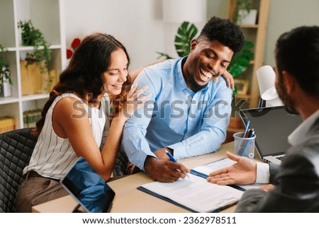 Young Latin American couple signing a contract with an agent in the office