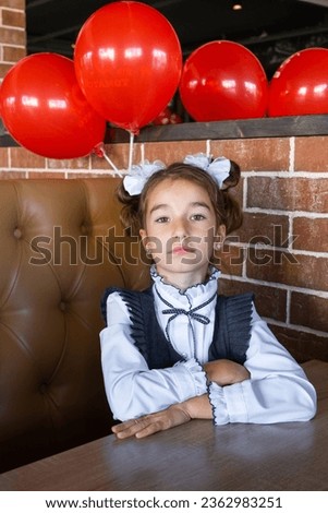 Portrait of a girl student of the 1st grade school with white bows in a dress unifor at the school desk. Back to school, September 1, First - grade. Primary education, elementary class.  Royalty-Free Stock Photo #2362983251