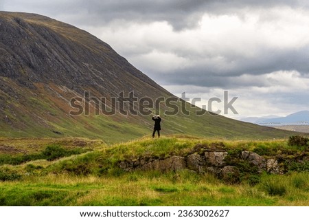 A woman taking pictures of the wonderful mountain scenery of the Glencoe Valley, Scotland.