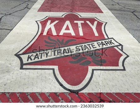 Katy Trail State Park sign on the street crossing in Boonville, Missouri. Katy trail is the nation's longest rails-to-trails project, 237 mile bike trail, stretching from the Machens to Clinton. Royalty-Free Stock Photo #2363032539