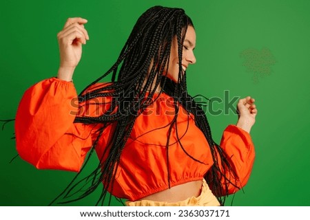 Happy young woman with dreadlocs dancing and smiling against green background Royalty-Free Stock Photo #2363037171