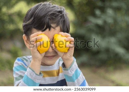 child holding 2 lemons. Fun photo child make a lemon eyes. Child boy Smiling face boy happy. Close-up photo.