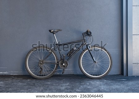 Bicycle leaning against a gray wall with copy space. Side view. Royalty-Free Stock Photo #2363046445