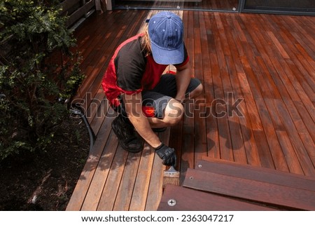 Ipe hardwood deck annual refreshing, man with paintbrush applying natural nourishing oil on cleaned and sanded Ipe decking terrace boards Royalty-Free Stock Photo #2363047217