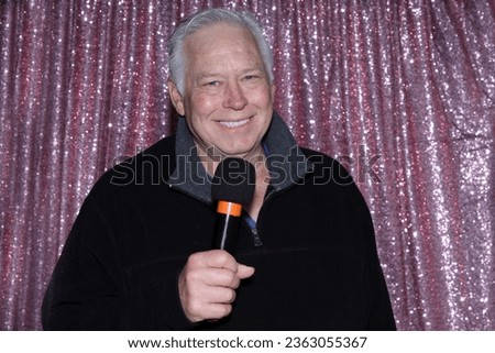 Lounge Singer. Photo Booth. A man with a Microphone Sings and Tells Jokes to entertain the crowd while he is in a Photo Booth waiting for his Pictures to be taken. Photo Booths are great for parties. 