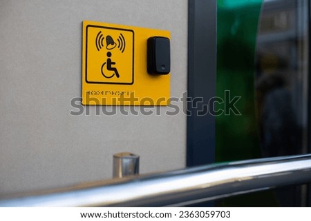 Disabled person sign with braille text and a panel with a button to call staff for assistance at the entrance to the building
